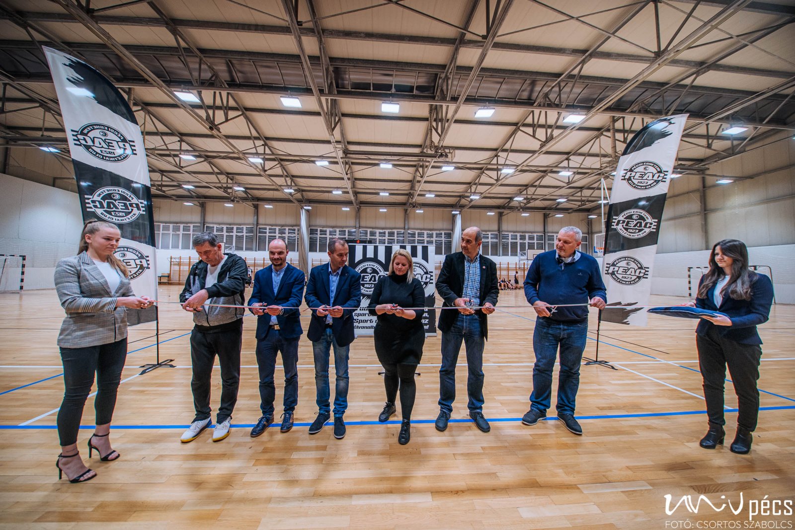 A nemzeti színű szalagot balról Czéh László szakosztályvezető, Hoffbauer Márk a PEAC ügyvezető igazgatója, Ács Pongrác, a PEAC elnöke, Antalné Papp Erika, Dr. Papp Gábor lánya, Trócsányi András, a Természettudományi Kar dékánhelyettese és Janovics László, a Baranya Megyei Kosárlabda Szövetség elnöke vágta át.